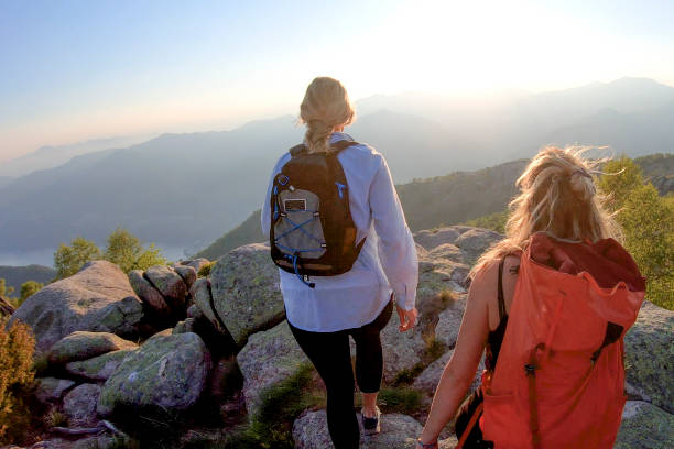 duas mulheres mochileiros caminham para a luz do sol em uma montanha - 5659 - fotografias e filmes do acervo