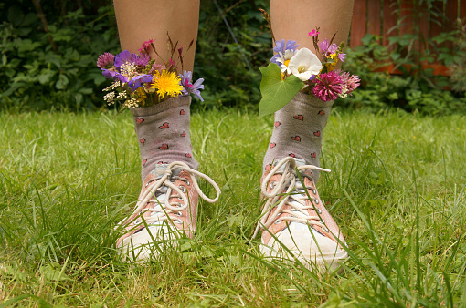feet in shoes sneakers with flowers in summer