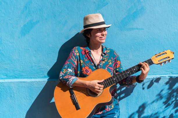 musikerin mit gitarre auf einer straße - street musician stock-fotos und bilder