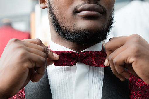 Detail of black man adjusting the bow tie on tailor shop