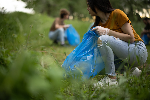 Young volunteers collecting garbage from forest in garbage bags
