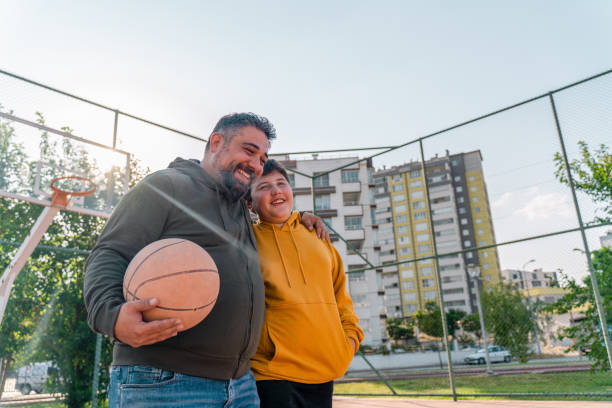 成熟した男と彼の息子は公共の公園を歩いて - basketball teenager nature outdoors ストックフォトと画像