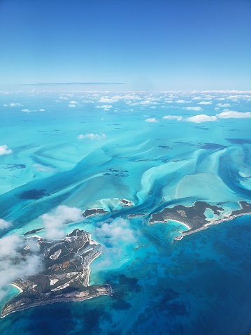 An aerial view of Bock Cay, Young Island and other nearby Bahamian Islands, just north of the Exumas. The small clouds cast shadows on the teal blue waters.