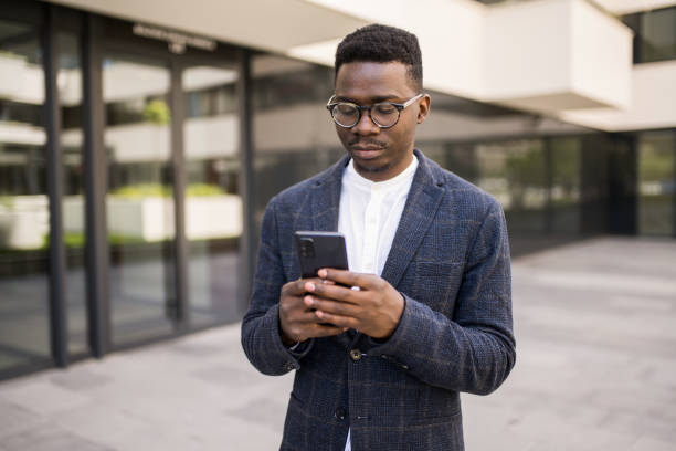 istock Young businessman using phone outside of an office building. 1336793443