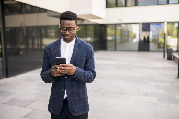 istock Young businessman using phone outside of an office building. 1336793471