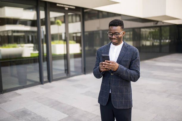 istock Young businessman using phone outside of an office building. 1336793482