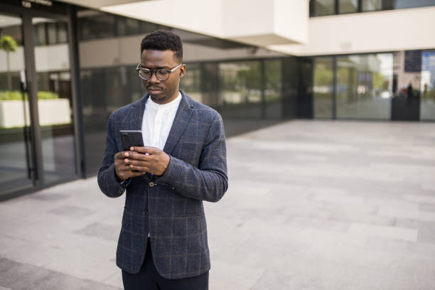 istock Young businessman using phone outside of an office building. 1336793489