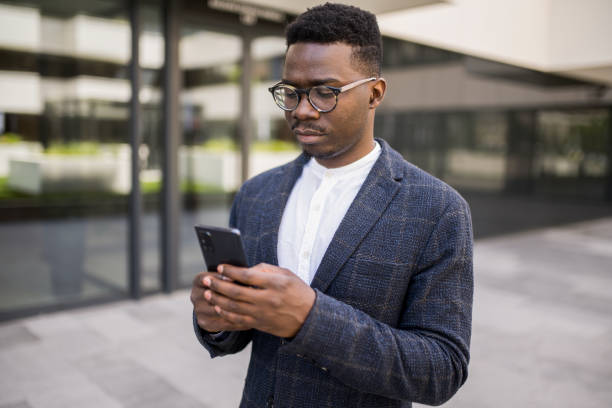 istock Young businessman using phone outside of an office building. 1336793494
