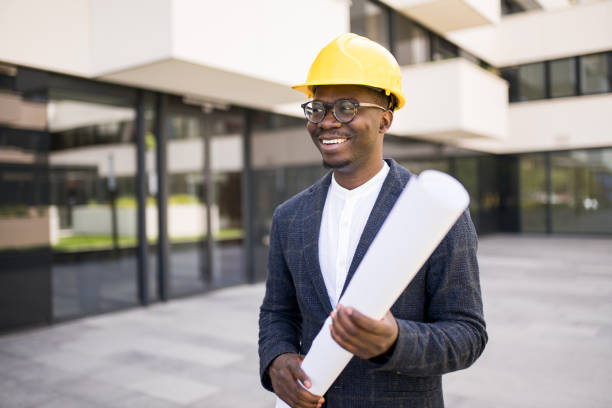 Happy young African American engineer standing at financial district.