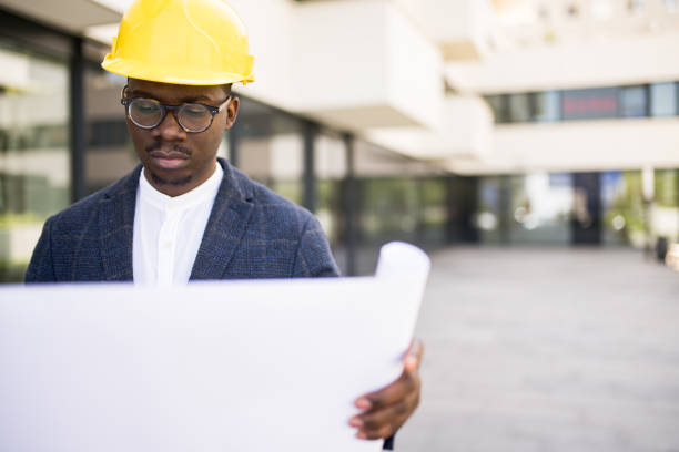 istock Young Architect examining a blueprint in front of an office building. 1336794378