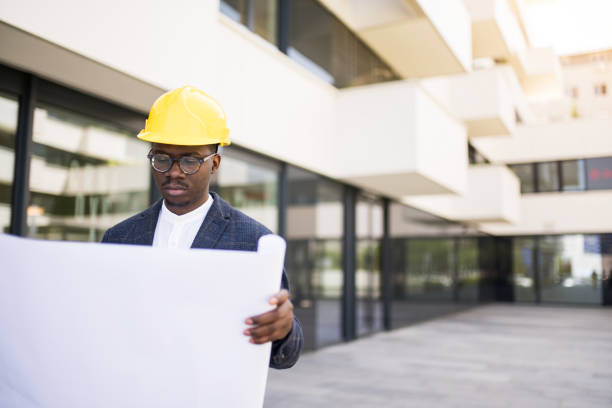 istock Young Architect examining a blueprint in front of an office building. 1336794418