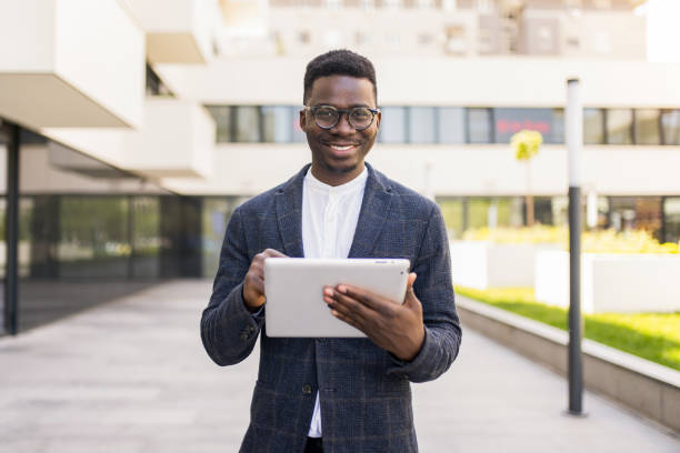 istock Happy young businessman using digital tablet outside of an office building. 1336794517