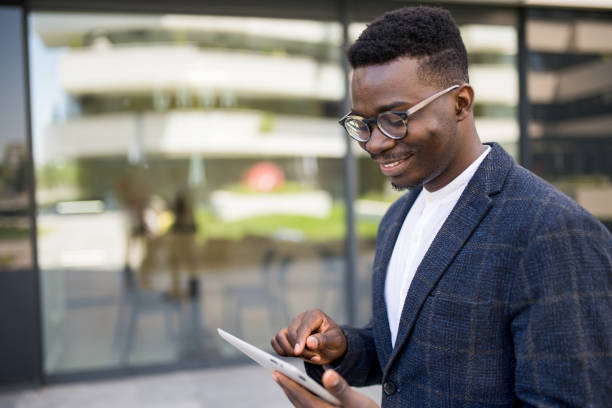 istock Happy young businessman using digital tablet outside of an office building. 1336794532