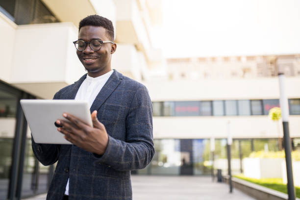 istock Happy young businessman using digital tablet outside of an office building. 1336794535