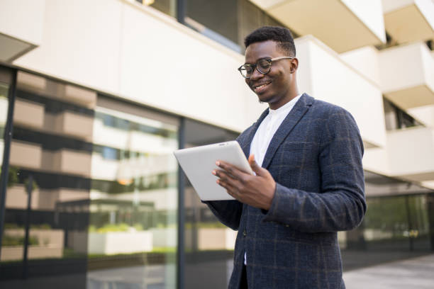 istock Happy young businessman using digital tablet outside of an office building. 1336794559
