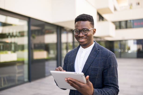 istock Young businessman using digital tablet outside of an office building. 1336795183