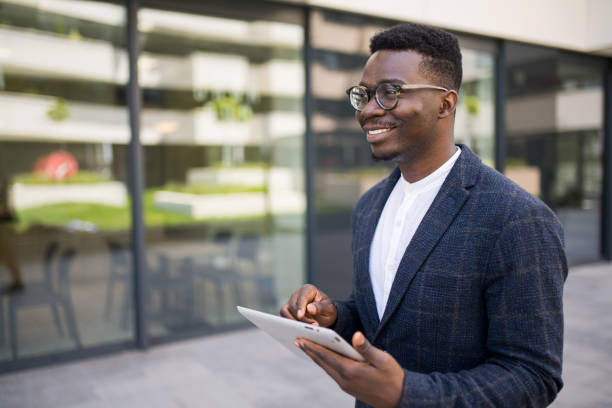 istock Young businessman using digital tablet outside of an office building. 1336795217