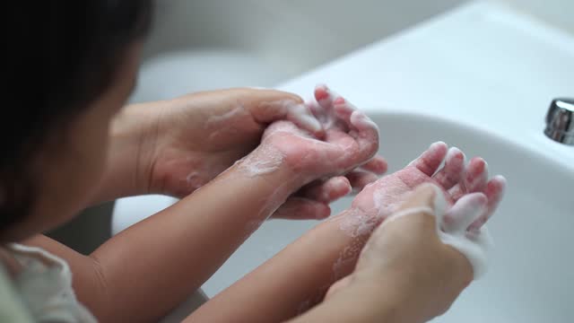 Mother washing her daughter's hands to prevent virus and germs and bacteria at Wash Basin Sink.