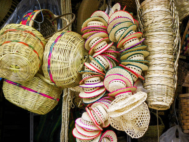 A pile of handmade traditional woven baskets and little panama hats made from straw, natural fiber, for sale at the outdoor market in Cuenca, Ecuador