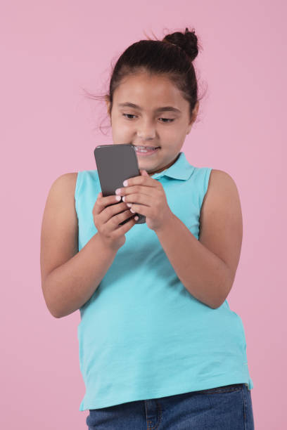 istock Little girl using phone on a pink background 1336802441