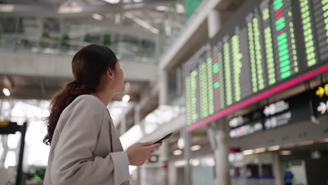 Asian Businesswoman looking at airport departure board