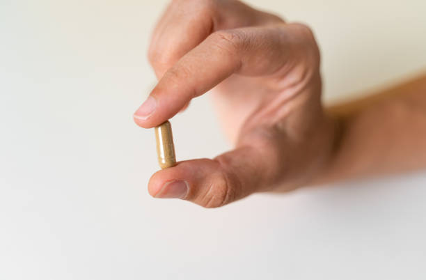 Close up hand with herb capsule on white background. Microdosing concept. Psychedelics therapy. Depression, anxiety treatment Close up hand with herb capsule on white background. Microdosing concept. Psychedelics therapy. Depression, anxiety treatment . High quality photo lsd trip stock pictures, royalty-free photos & images