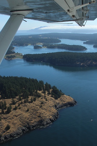 From a small plane on a sunny day, many small islands located in the San Juan Island area are visible.