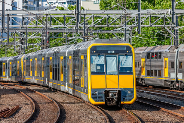 Modern double-deck (bi-level) electric commuter train with yellow front and doors Modern double-deck (bi-level) electric commuter train with yellow front and doors passing an older  train also with yellow doors as they approach major city station: track is tree-lined. ID and logos edited. Yellow is dominant colour electric train photos stock pictures, royalty-free photos & images