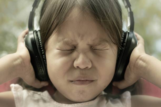ein kleines kind, das angst vor lauten geräuschen hat, empfindlich auf geräusche reagiert und die ohren bedeckt. autismus und schlechte sensorische verarbeitung. - child asian ethnicity little girls toddler stock-fotos und bilder