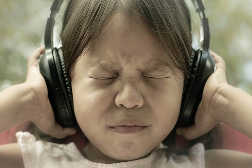 Un niño pequeño temeroso del ruido fuerte, sensible al sonido, que cubre los oídos. Autismo y mal procesamiento sensorial. photo