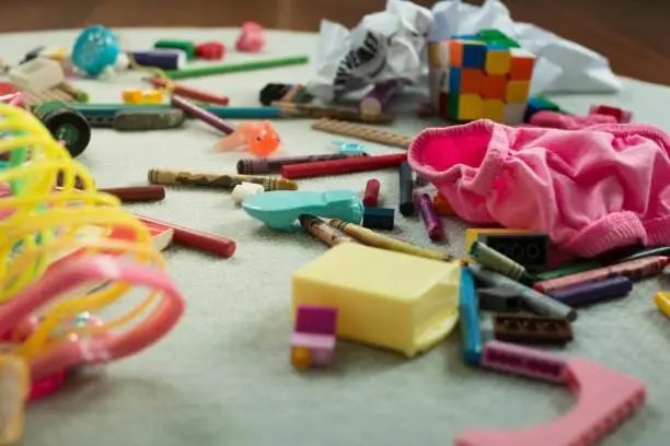 Toys and kids mess scattered everywhere on the floor at home.