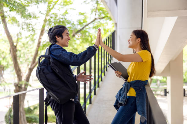 istock Two Asian university students walking and conversing to class in a magnificent campus building's walkway. 1336821334