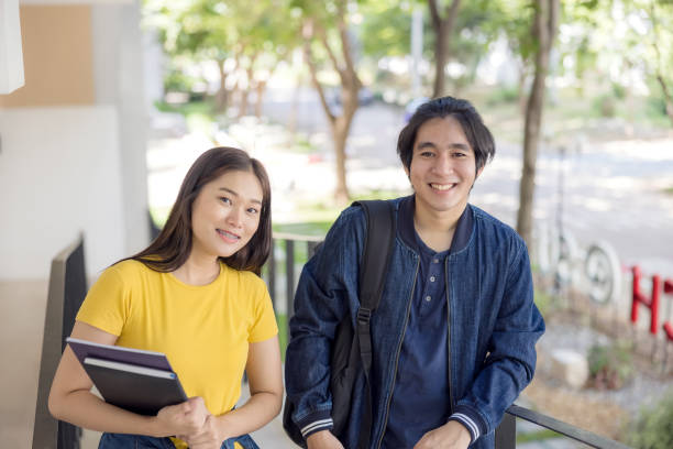 istock Two Asian university students walking and conversing to class in a magnificent campus building's walkway. 1336821336