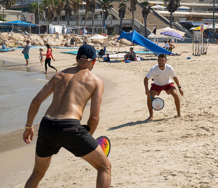 Tel Aviv, Israel - August 15th, 2021: Two young men playing matkot on the Tel Aviv, Israel, beach, on a clear, sunny day.