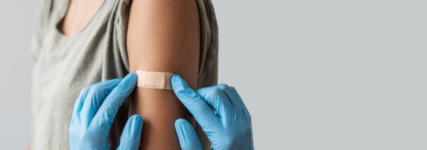 un travailleur médical met un pansement sur le bras féminin après la vaccination contre le covid-19 - primary care photos et images de collection