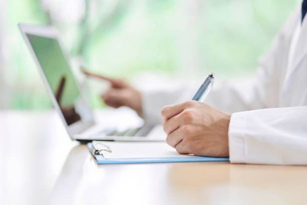 A male doctor who looks up on a computer and takes notes