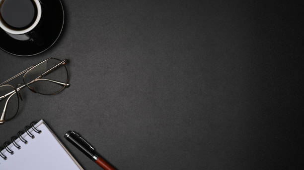 istock Top view glasses, coffee cup and notebook on black leather with copy space. 1336827481