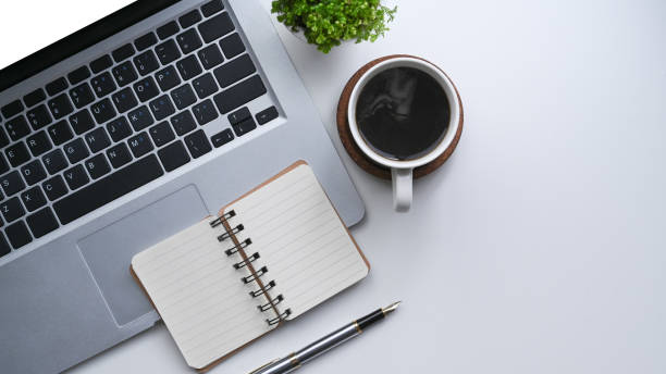 istock Computer laptop, notebook and cup of coffee on simple workspace. 1336828273