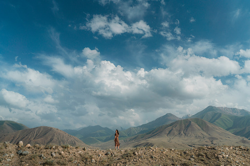Young Caucasian woman standing on the background of  Tien Shan mountains in Kyrgyzstan in summer