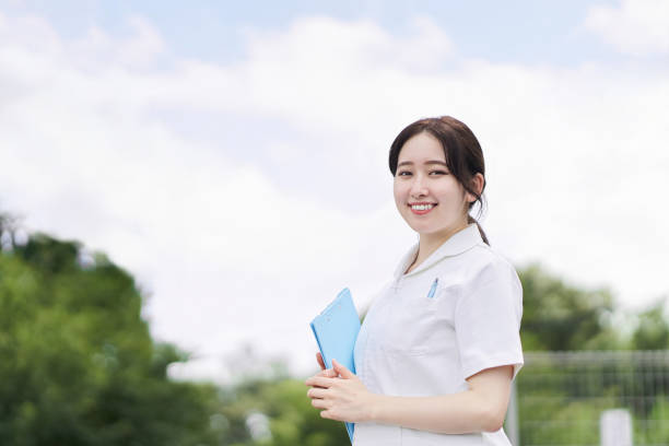 istock Female nurse standing with a smile on a blue sky background 1336832691