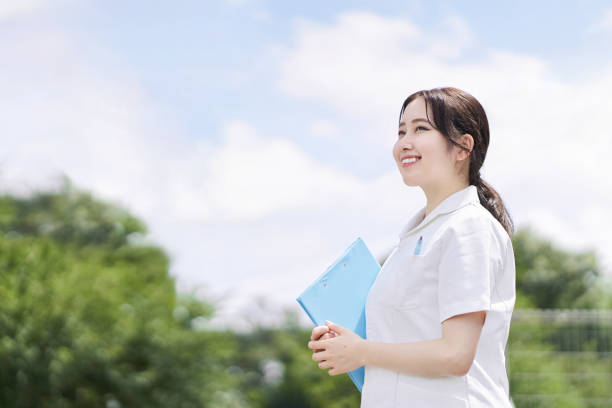 �青い空の背景に笑顔で立っている女性看護師 - japanese ethnicity train women asian ethnicity ストックフォトと画像