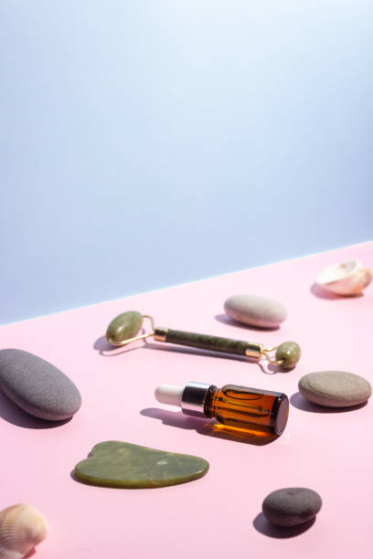 istock Cosmetic product in a glass bottle with a pipette and gua sha e scraper and roller. Smooth stones nearby. The concept of skin care, cosmetology. 1336833531