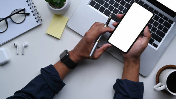 istock Businessman holding pen and using smart phone at his workspace. 1336836483