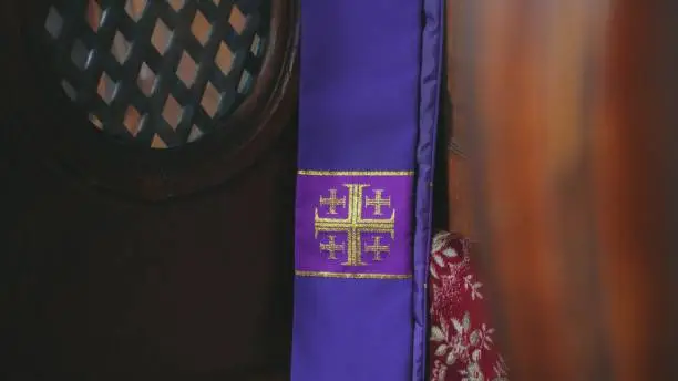 Purple Catholic Priest Stole with Embroidered Jerusalem Cross Hanging in Church Confessional Close Up