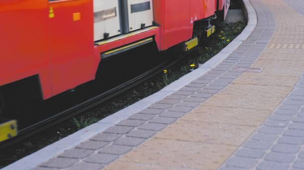 Red City Tram Passing By Commuters Platform with Tactile Paving Improving Accessibility for Low Vision and Blind People