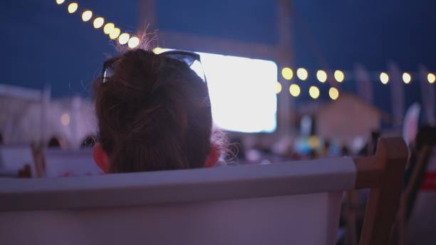 夏の映画祭中に野外ビーチシネマで映画を見る白人女性 - music festival outdoors popular music concert spectator ストックフォトと画像