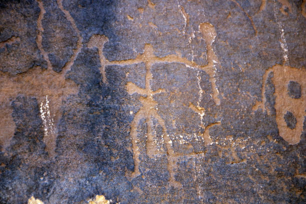 a petroglyphic image of a man holding tools on the graffiti rock (qaryat al asba) - carved rock imagens e fotografias de stock