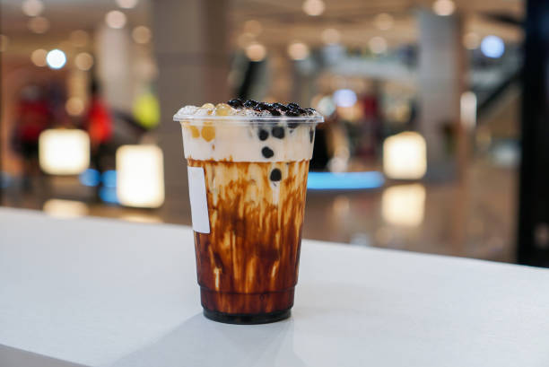 Brown sugar bubble drink. A plastic cup of fresh milk and brown sugar syrup, topped with boba or bubble tapioca pearl on white table. bubble tea photos stock pictures, royalty-free photos & images