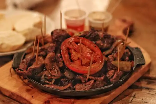 Portion of steak with tomato and onion on a rustic board