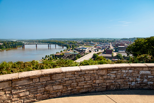 This high-angle view from Fort Boreman Scenic Overlook shows off Parkersburg West Virginia and the Might Ohio River on a clear blue morning. There are a couple of bridges in the distance and a Y-shaped highway.  The river divides Ohio from West Virginia